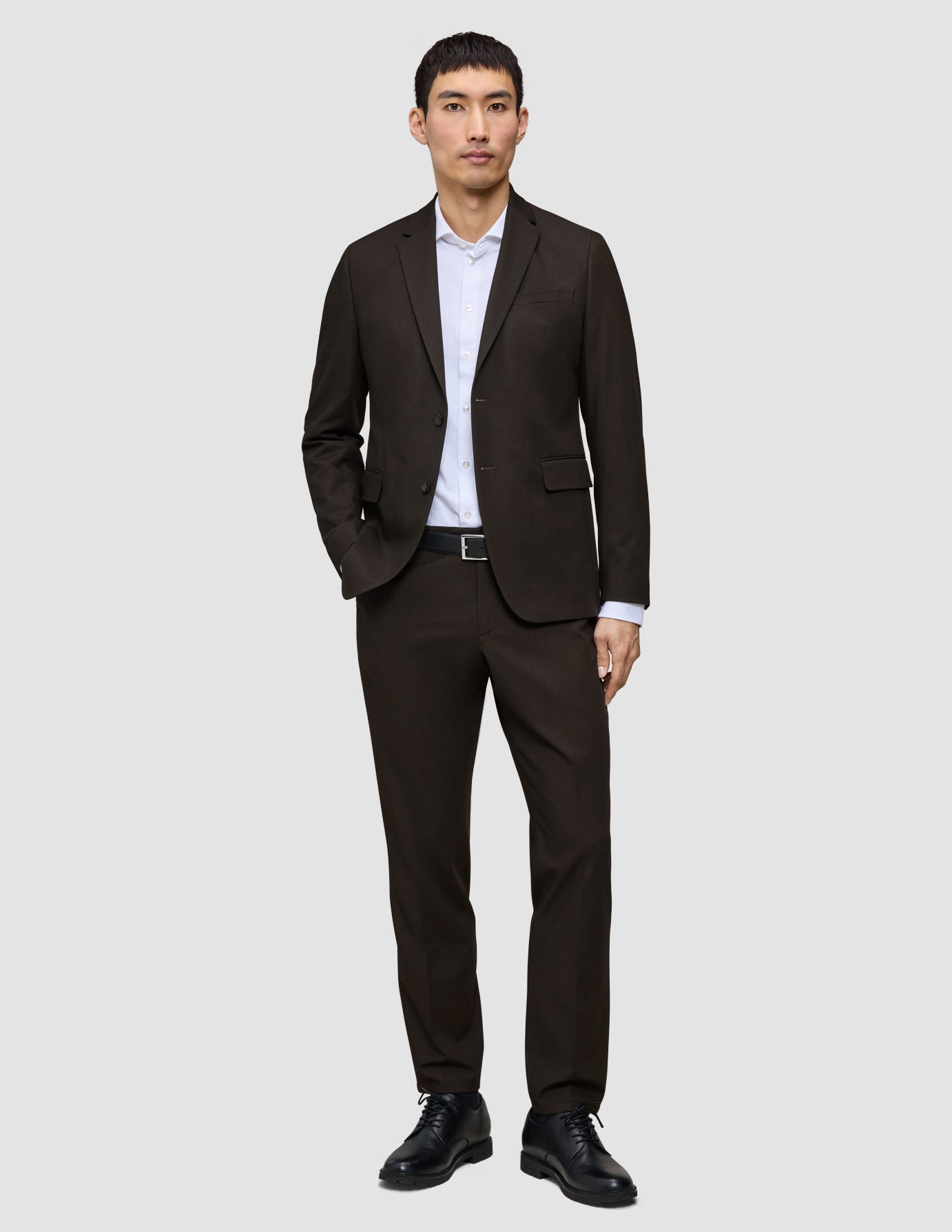 A man wearing a Motion Blazer Regular Cognac tailored blazer, paired with a white button-down shirt, black belt, and black dress shoes.